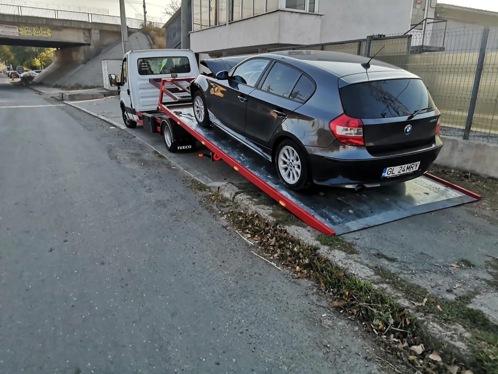 Autoturism compact fixat pe platformă, preluare de la domiciliu.