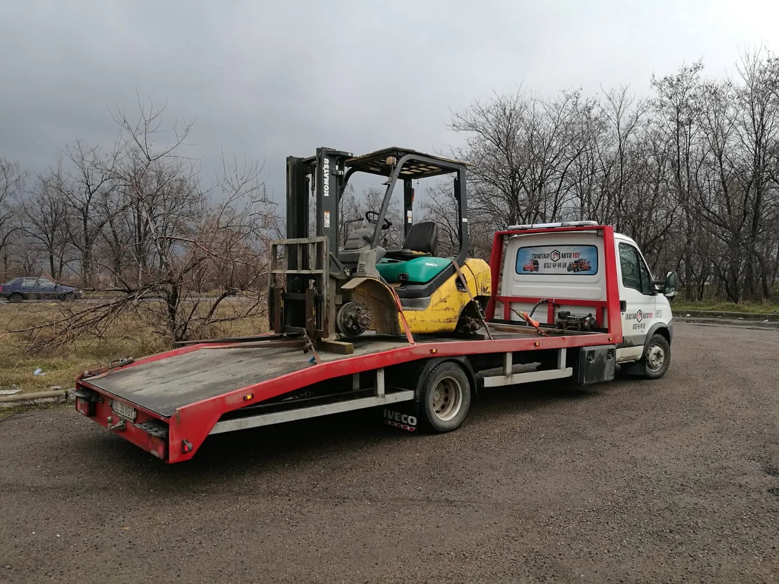 Motostivuitor transportat pe platformă, utilaj industrial.